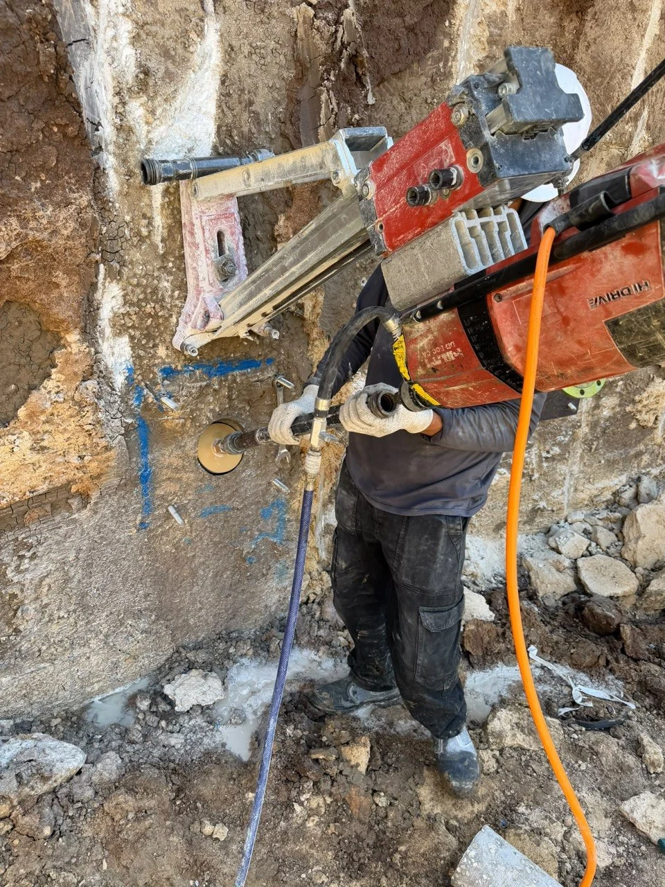 עובד מבצע קידוח בבטון באמצעות מערכת קידוח יהלום